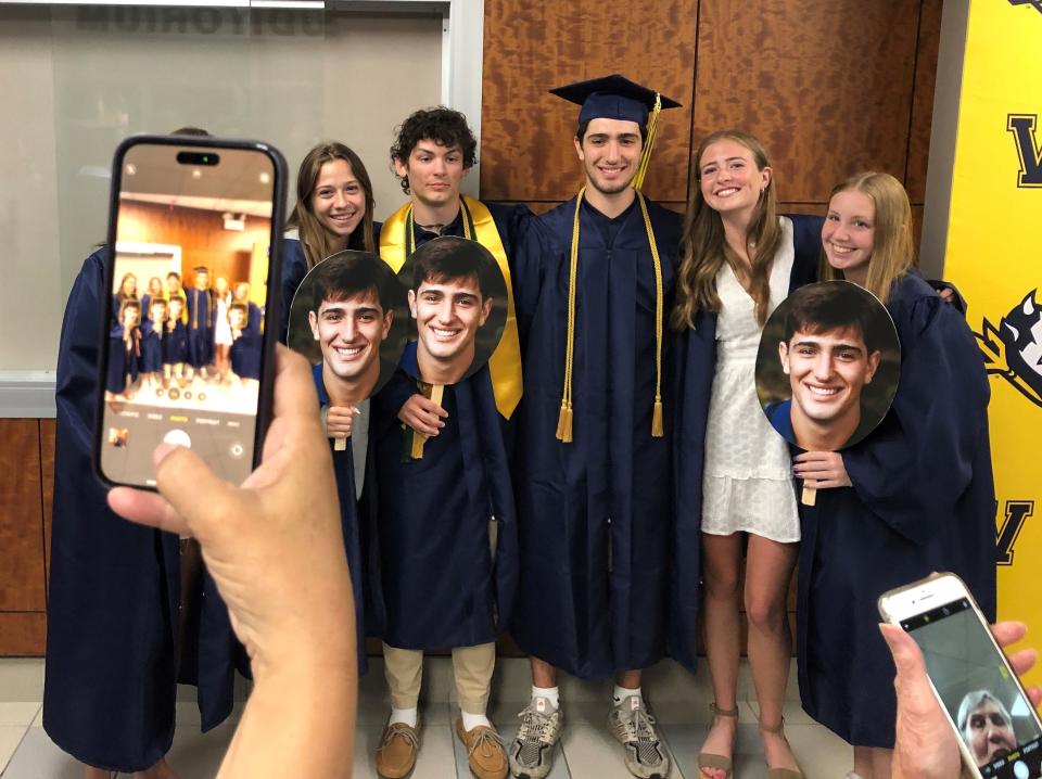 Victor High School senior lacrosse players pose with family and friends after receiving their diplomas in a special graduation ceremony Monday night.