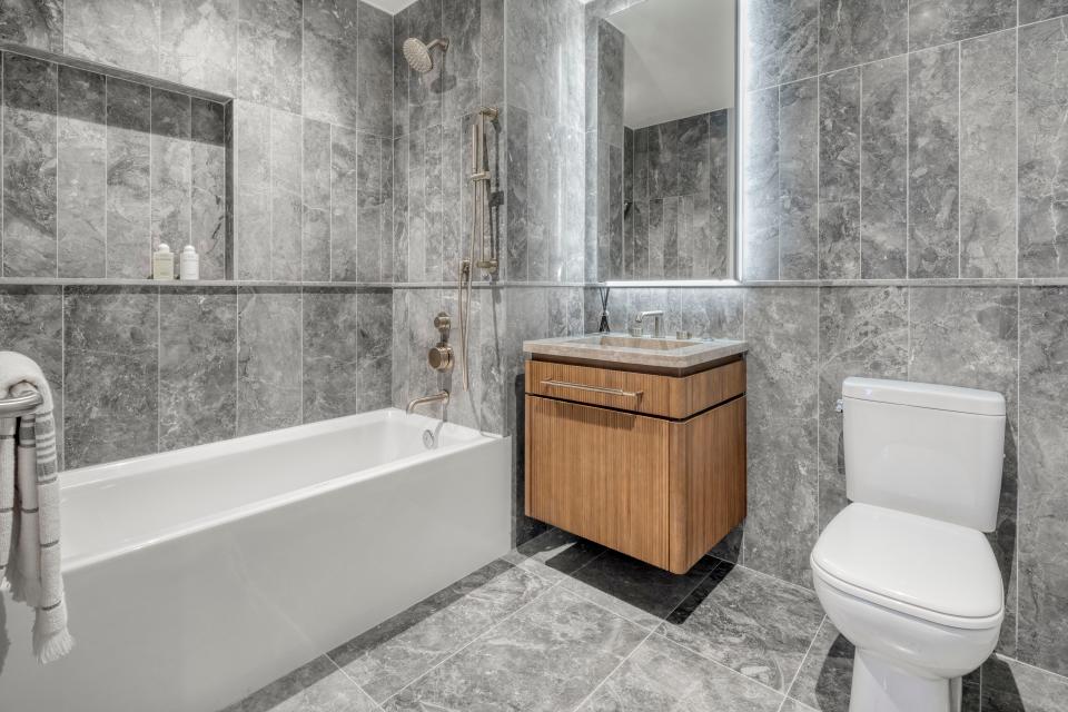 the bathroom with tiles on wall and floor, a toilet, and a brown sink