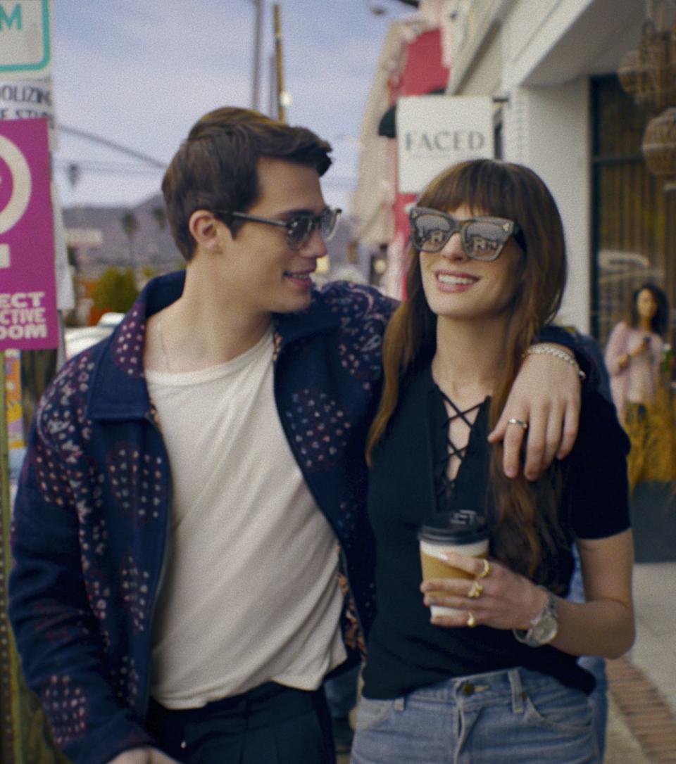 the idea of you, nicholas galitzine and anne hathaway with their arms around each other and wearing sunglasses