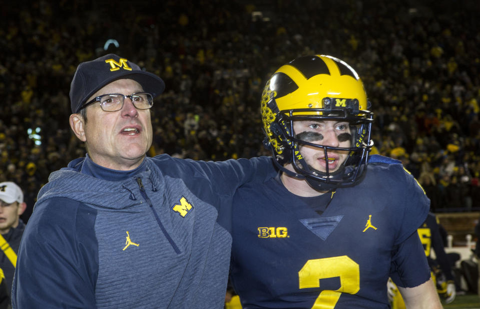 Michigan head coach Jim Harbaugh, left, puts an arm around Michigan quarterback Shea Patterson, right, after an NCAA college football game against Indiana in Ann Arbor, Mich., Saturday, Nov. 17, 2018. Michigan won 31-20. (AP Photo/Tony Ding)