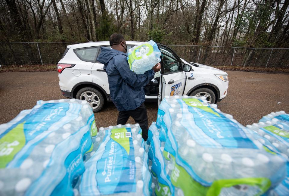 Derrick Kelly gives a Jackson resident a case of water at Forest Hill High School in Jackson, Miss., Monday, March 1, 2021. Water is still being distributed due to water outages around the city after February's winter storm.