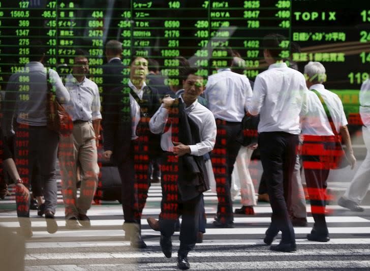 Passersby are reflected on a stock quotation board at a brokerage in Tokyo, Japan, September 29, 2015. REUTERS/Issei Kato