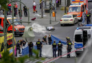 Police officers cover a dead body after a car crashed into a crowd of people in central Berlin, Germany, Wednesday, June 8, 2022. (AP Photo/Michael Sohn)