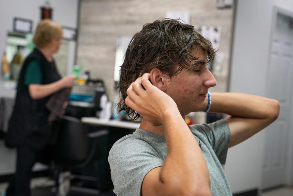Jacob Terechenok, 16, of Canton, reacts after perm curling rods are removed from his hair at Anthony's Hair Inc in Allen Park on July 25, 2023.