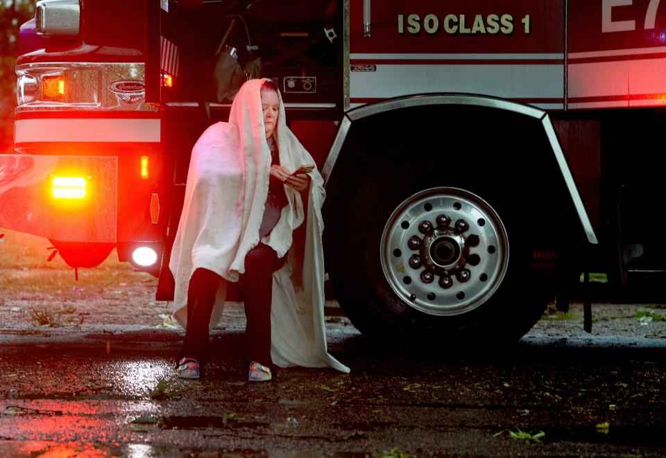 Linda Eskew of Springfield sits on the step of a firetruck after being looked over by firefighters Thursday, June 29, 2023. She narrowly escaped be crushed when a tree fell on her car she was driving on the 200 block of Pine Street.