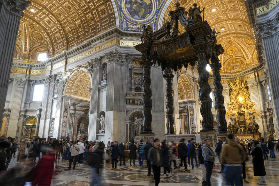 Visitors walk by the 17th century, 95ft-tall bronze canopy by Giovan Lorenzo Bernini surmounting the papal Altar of the Confession in St. Peter's Basilica at the Vatican, Wednesday, Jan. 10, 2024. Vatican officials unveiled plans Thursday, Jan.11, for a year-long, 700,000 euro restoration of the monumental baldacchino, or canopy, of St. Peter's Basilica, pledging to complete the first comprehensive work on Bernini's masterpiece in 250 years before Pope Francis' big 2025 Jubilee. (AP Photo/Andrew Medichini)
