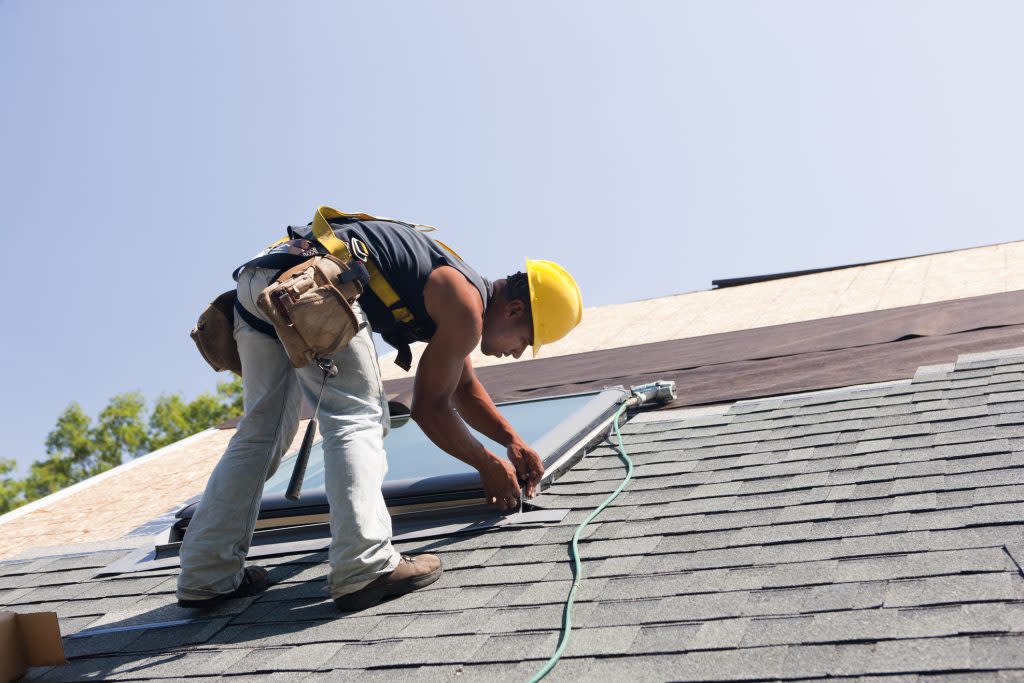 A worker installs solar energy panels on a roof. (Getty Images)