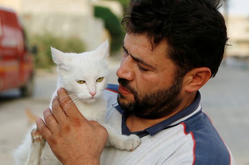 FILE PHOTO: Alaa, an ambulance driver, carries a cat in Masaken Hanano in Aleppo