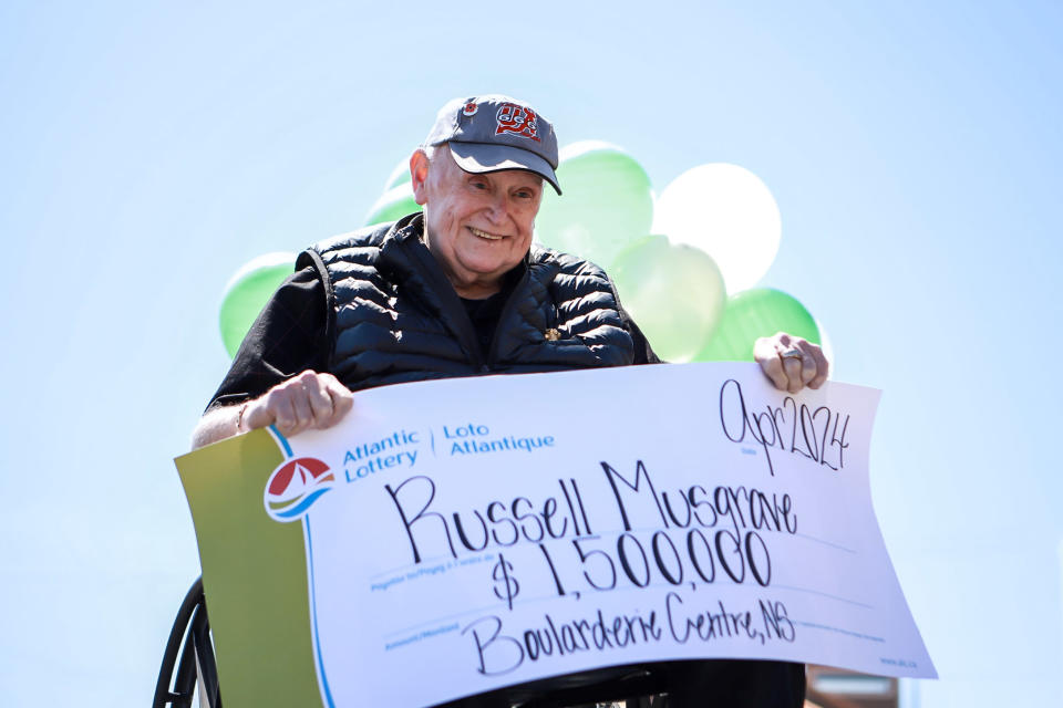 Man in a wheelchair holding a 1.5 million lotto cheque.
