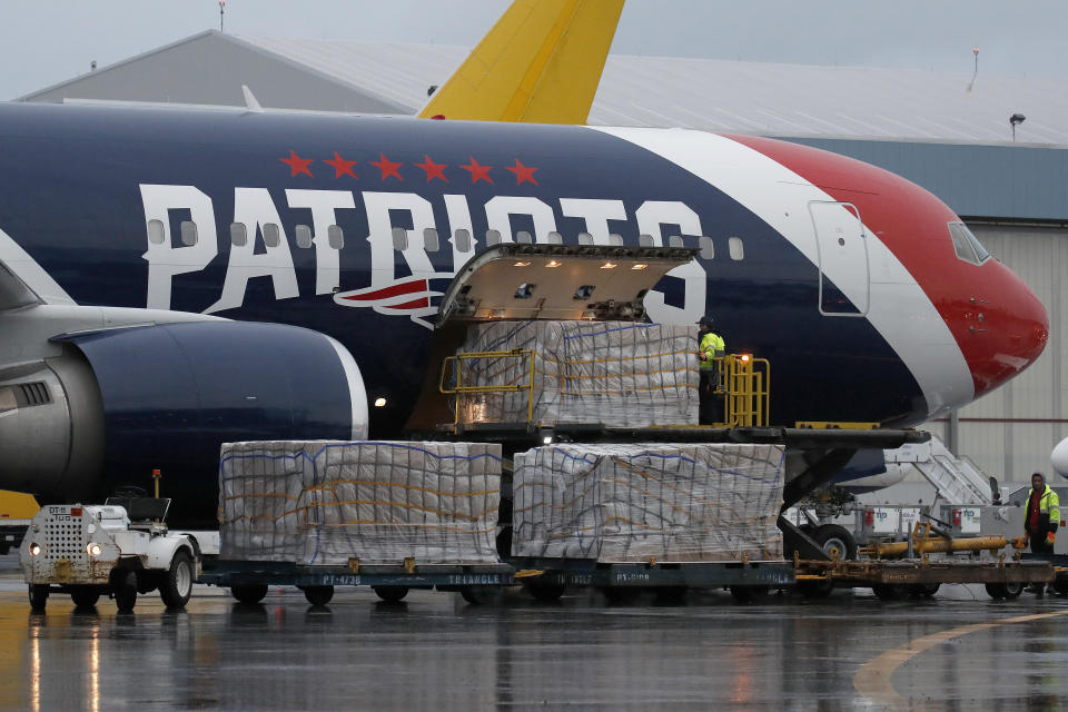 Palettes of N95 respirator masks are off-loaded from the New England Patriots football team's customized Boeing 767 jet on the tarmac, Thursday, April 2, 2020, at Logan Airport in Boston, after returning from China. The Kraft family deployed the Patriots team plane to China to fetch more than one million masks for use by front-line health care workers to prevent the spread of the coronavirus. (AP Photo/Elise Amendola)