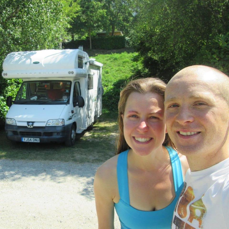 Esther Dingley and Dan Colegate smile together in front of their camper van. 