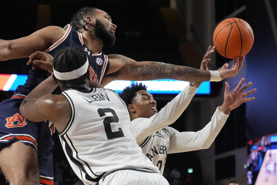 Auburn forward Johni Broome reaches for a rebound past Vanderbilt forward Ven-Allen Lubin (2) and guard Tyrin Lawrence, right, during the second half of an NCAA college basketball game Wednesday, Jan. 17, 2024 in Nashville, Tenn. Auburn won 80-65. (AP Photo/George Walker IV)