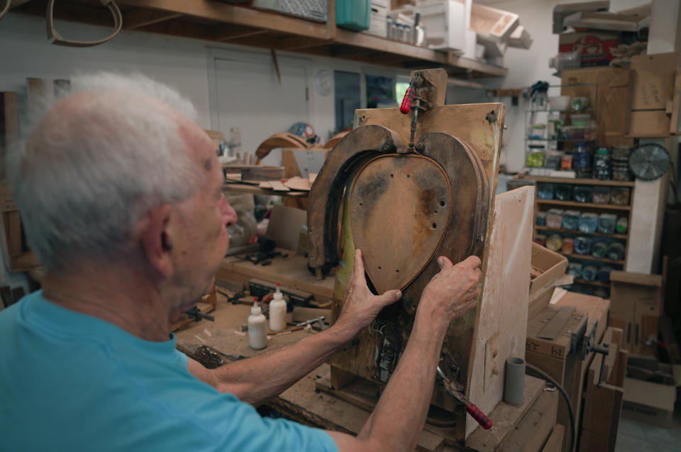 Mike Dulak bends a piece of wood to shape the frame of a mandolin, in his workshop in Rocheport, Mo., Friday, Sept. 8, 2023. Over the past 30 years, Dulak has made thousands of mandolins, and says he finds a sense of spirituality in working with the wood, just as he does playing his guitar. But Dulak, along with the largest group of Americans, does not associate himself with any religion. (AP Photo/Jessie Wardarski)