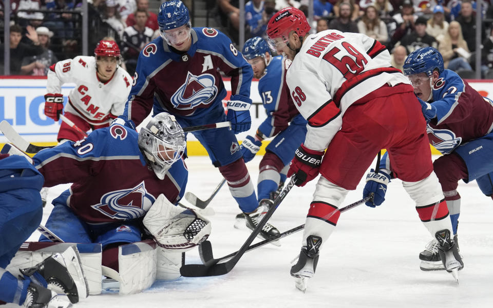 Colorado Avalanche goaltender Alexandar Georgiev, front left, stops a shot off the stick of Carolina Hurricanes left wing Michael Bunting, front right, in the second period of an NHL hockey game Saturday, Oct. 21, 2023, in Denver. (AP Photo/David Zalubowski)