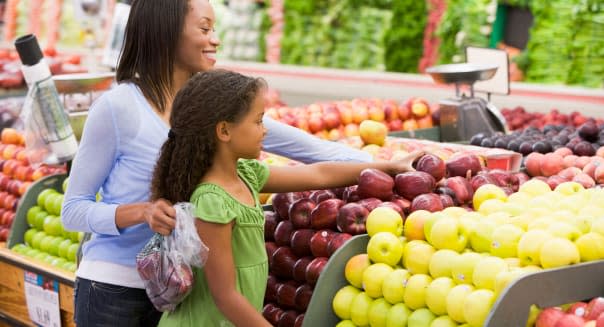 Woman and daughter shopping for apples at a grocery store