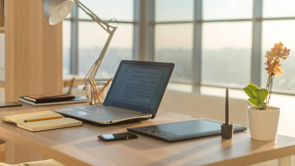 Side view picture of studio workplace with blank notebook, laptop.