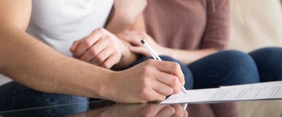 Close up of couple signing mortgage documents