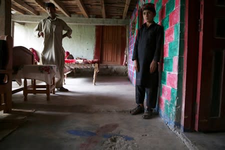 Raja Nauman, 10, stands next to a crater on the floor of his house, caused by a cluster bomb that according to family looked like a toy and exploded in the hands of a child, in village Jabri, in Neelum Valley