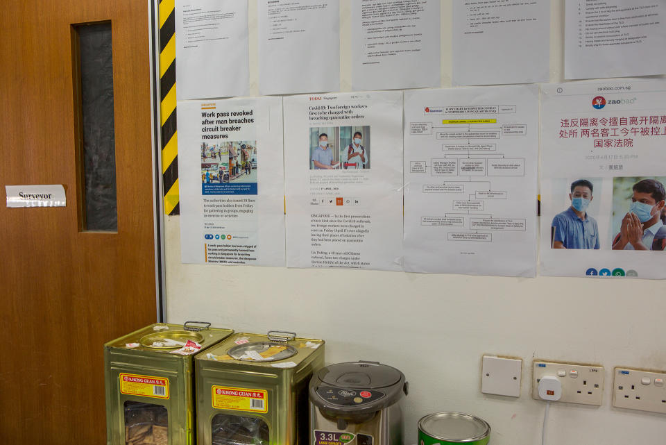 News articles on foreign workers who have been penalised for flouting circuit breaker measures seen on a wall inside the temporary living quarters. (PHOTO: Dhany Osman / Yahoo News Singapore)