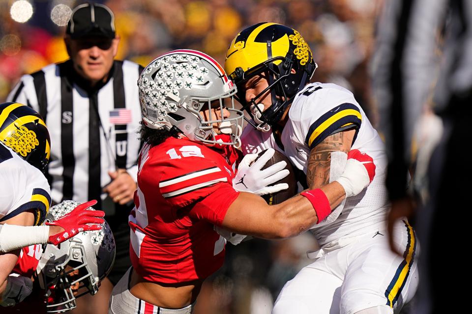 Nov 26, 2022; Columbus, Ohio, USA;  Ohio State Buckeyes safety Lathan Ransom (12) tackles Michigan Wolverines running back Blake Corum (2) during the first half of the NCAA football game at Ohio Stadium. Mandatory Credit: Adam Cairns-The Columbus Dispatch