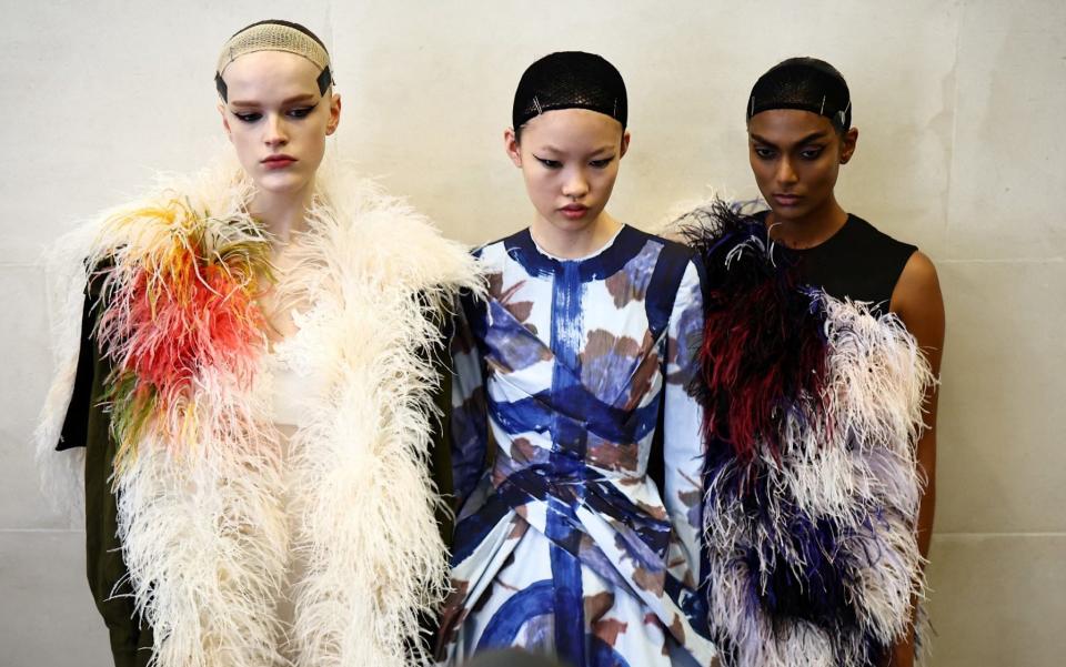 Models posing backstage ahead of a catwalk