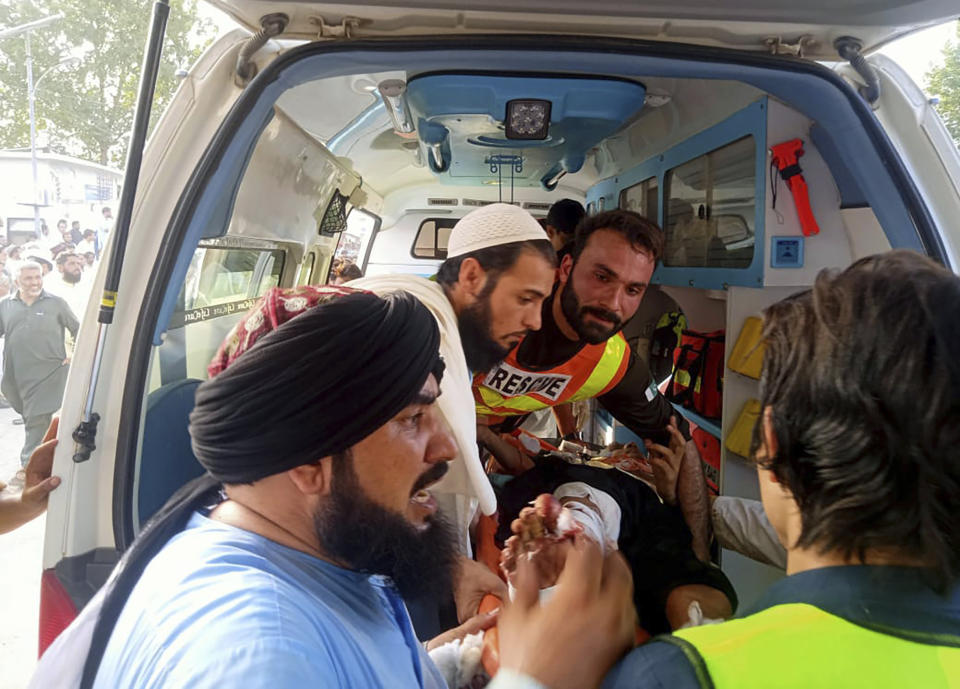 In this photo provided by Rescue 1122 Head Quarters, rescue workers carry a wounded man after a bomb explosion in the Bajur district of Khyber Pakhtunkhwa, Pakistan, Sunday, July 30, 2023. A powerful bomb ripped through a rally by supporters of a hard-line cleric and political leader in the country’s northwestern Bajur district that borders Afghanistan on Sunday, killing at least 10 people and wounding more, police said. (Rescue 1122 Head Quarters via AP)