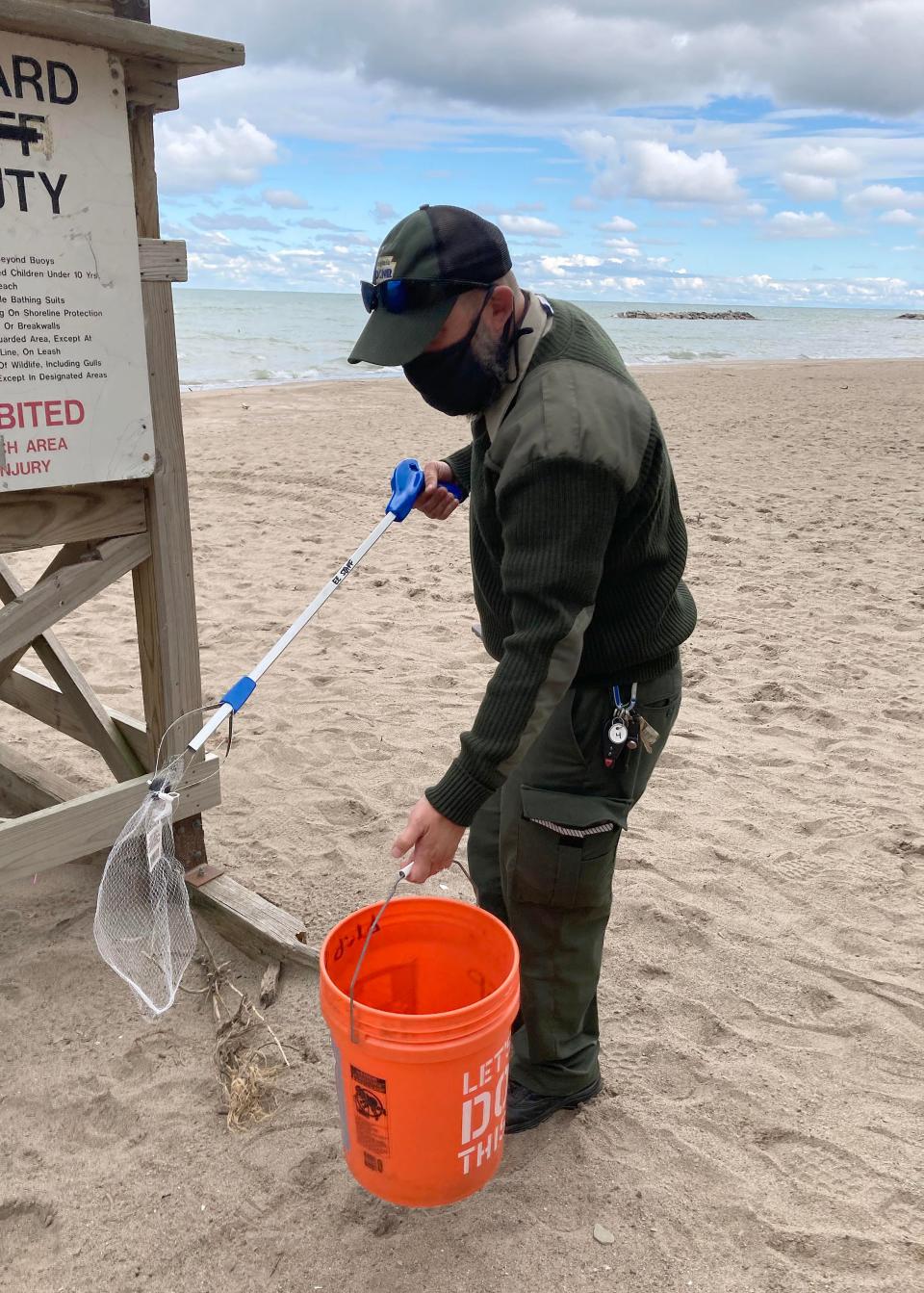 Brian Gula, an environmental education specialist at Presque Isle State Park, picks up a piece of plastic netting littering Beach 6. He says it's the kind of trash that can be especially harmful to wildlife, which can get caught in it.