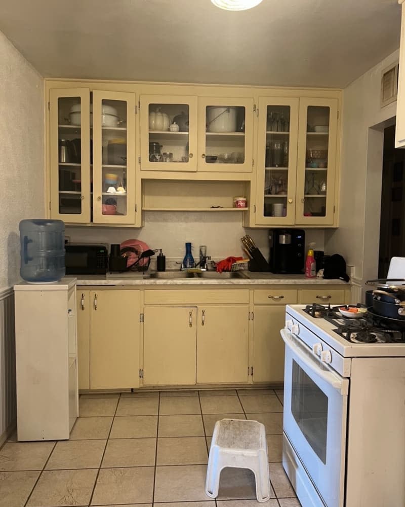 Kitchen with light neutral cabinetry, white oven, and water cooler.