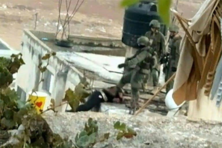 An image grab taken from an AFPTV video shows an Israeli soldier pushing an apparently dead Palestinian off a rooftop during a raid in the occupied West Bank (-)