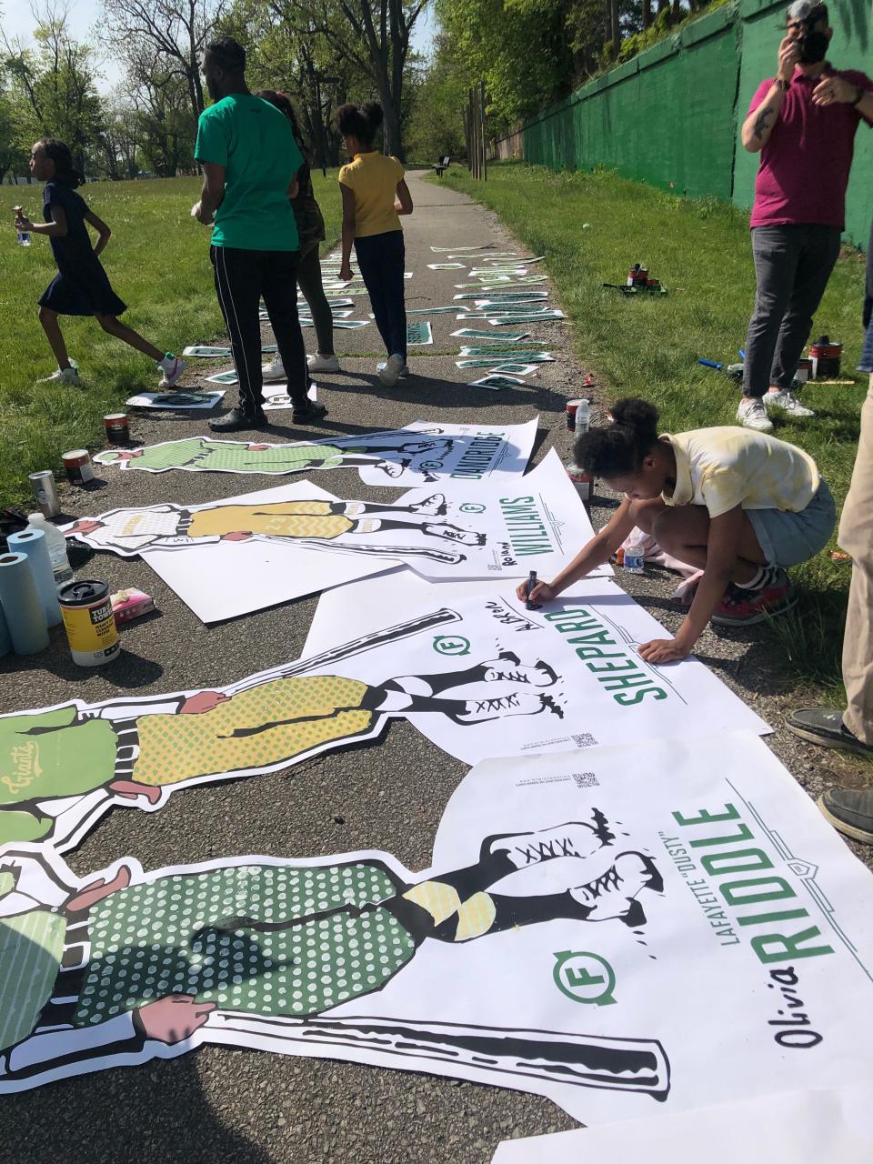Boys and Girls Club members sign the artwork of Foundry Giants players before it is placed on the Foundry Field wall. They designed the likenesses.
