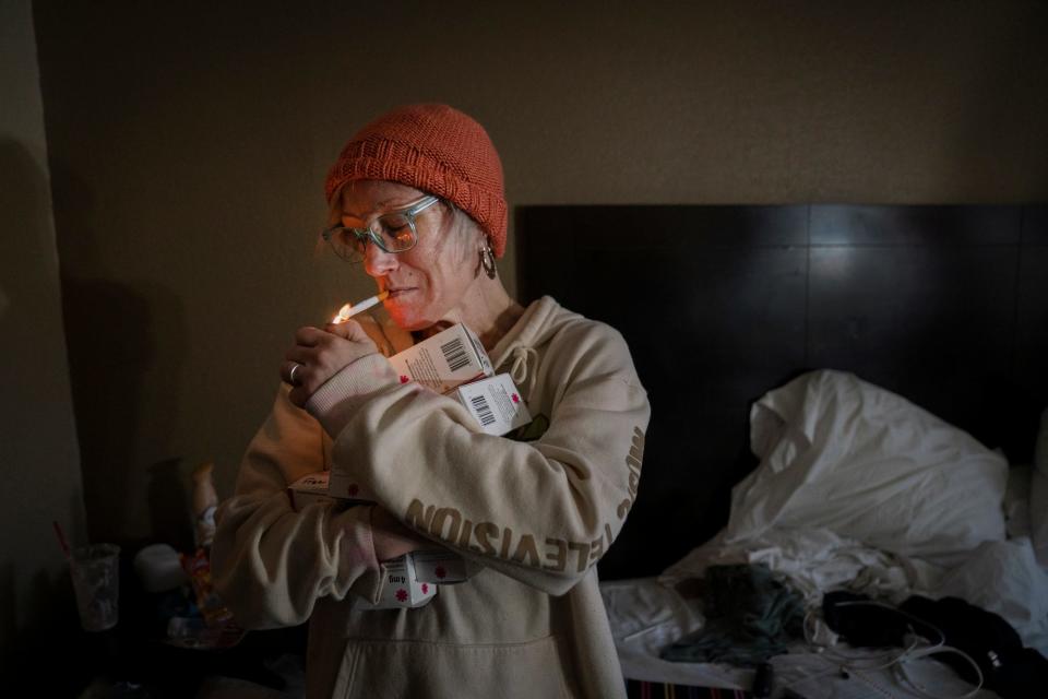Amanda lights a cigarette in her motel room on Monday, Oct. 17, 2022 in Detroit before she distributes what Narcan she has left to motel residents. She had already distributed clean needles to them.