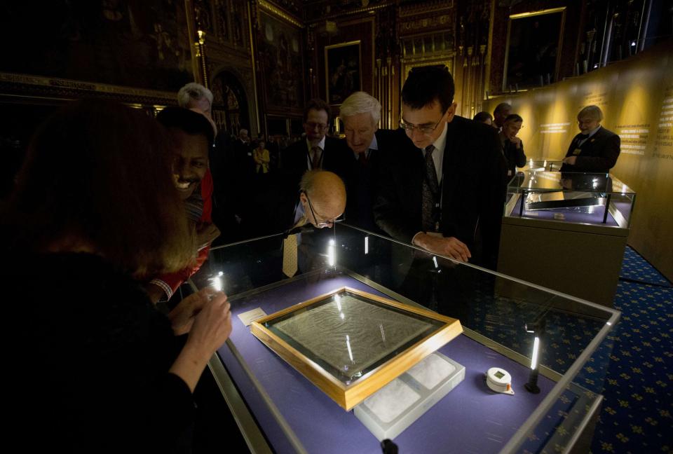 People look at the four surviving original parchment engrossments of the 1215 Magna Carta, as they are displayed to mark the 800th anniversary of the sealing of the Magna Carta in 1215, in the Queen's Robing Room at the Houses of Parliament in London February 5, 2015. The original copies were displayed on Thursday for one day at the opening of the exhibition "Magna Carta and Parliament". REUTERS/Matt Dunham/pool (BRITAIN - Tags: POLITICS SOCIETY)