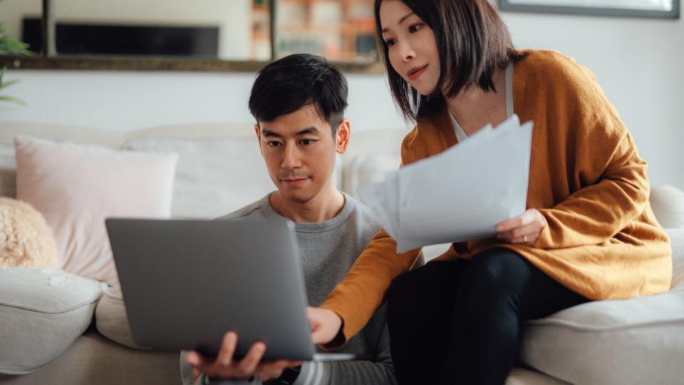 Young couple discussing financial bills while using laptop on sofa