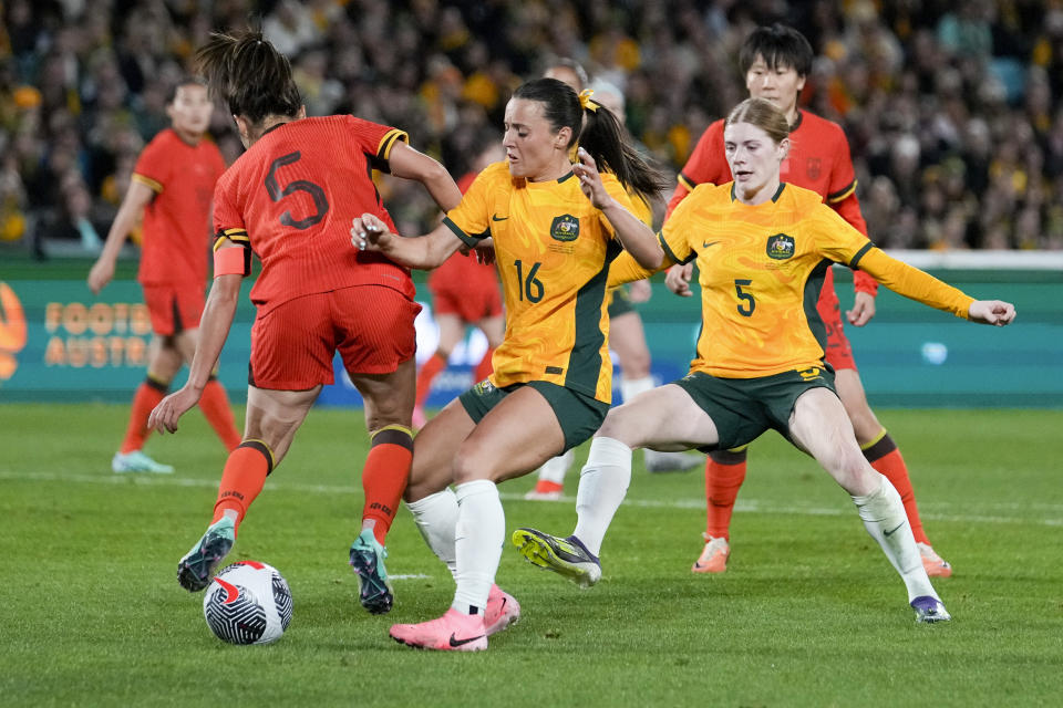 Australia's Hayley Raso, centre, and China's Wu Haiyan battle for the ball as Australia's Cortnee Vine, right, watches during the women's international soccer friendly between China and Australia at Stadium Australia, in Sydney, Monday, June 3, 2024. (AP Photo/Rick Rycroft)