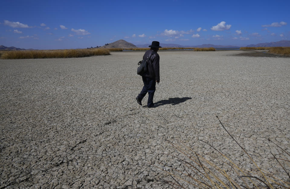 Un hombre aymara camina por el lecho seco y agrietado del lago Titicaca, en Huarina, Bolivia, el 27 de julio de 2023. El bajo nivel del agua en el lago está teniendo un impacto directo en la flora y la fauna locales y afecta a las comunidades locales que dependen de la frontera natural entre Perú y Bolivia para su sustento. (AP Foto/Juan Karita)