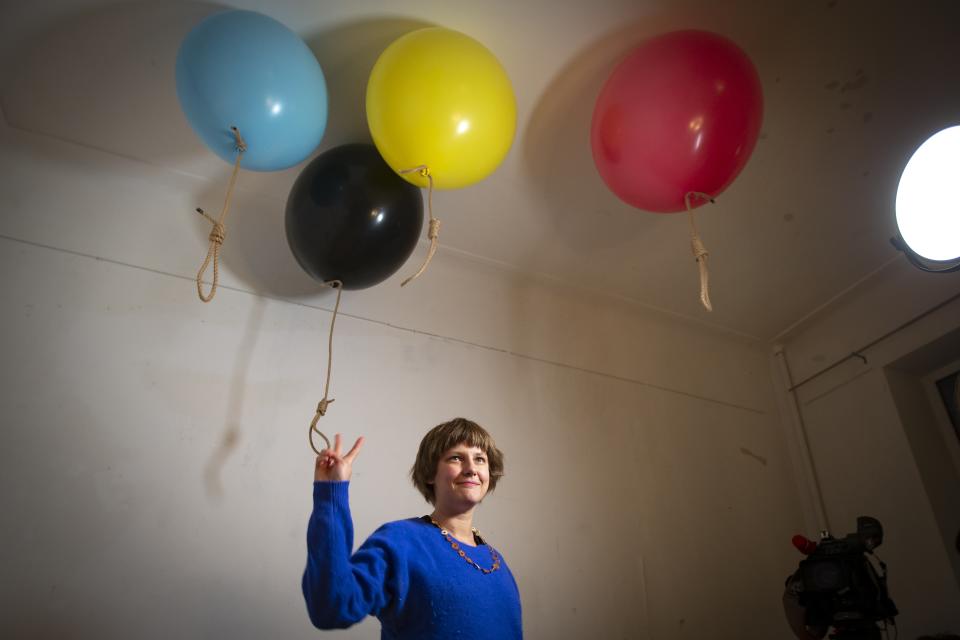 In this photo taken on Sunday, Oct. 27, 2019, Austrian artist Michele Pagel poses for a photo in front of her work showing rope nooses suspended from balloons bringing an issue often dismissed to the periphery of Russian society back to its center of attention at an opening ceremony of her exhibition in Moscow, Russia, Pagel 's show 'Polly wants a Cracker', focuses on domestic abuse. Moscow’s suburbs are the focus of a major international art exhibition that has just opened in the Russian capital. The exhibit uses contemporary art to explore the many hidden facets of life beyond the Russian capital’s nucleus. Austrian cultural attache says the ‘real’ Moscow where most of the city’s 12.6 million people live, is outside the center. (AP Photo/Alexander Zemlianichenko)