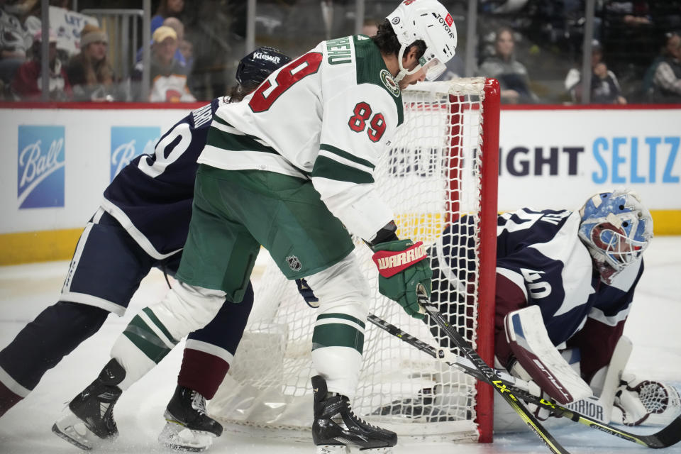 Minnesota Wild center Frederick Gaudreau, front left, wraps around the net as Colorado Avalanche defenseman Samuel Girard, back left, covers to put a shot on goaltender Alexandar Georgiev in the second period of an NHL hockey game, Wednesday, March 29, 2023, in Denver. (AP Photo/David Zalubowski)