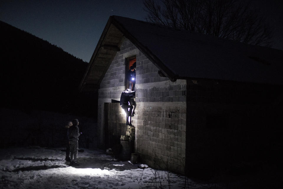 In this picture taken Saturday Dec. 14, 2019, a group of Afghan migrants enter an abandoned farm near the border with Croatia to use it as shelter before attempting to cross the border into the EU near Bihac, northeast Bosnia.(AP Photo/Manu Brabo)