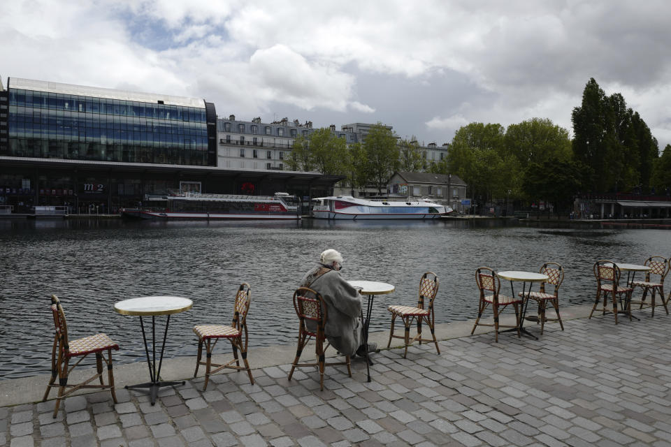 A woman sit at a cafe terrace along the Seine river Wednesday, May, 19, 2021 in Paris. Cafe and restaurant terraces reopened Wednesday after a six-month coronavirus shutdown deprived residents of the essence of French life — sipping coffee and wine with friends. (AP Photo/Rafael Yaghobzadeh)