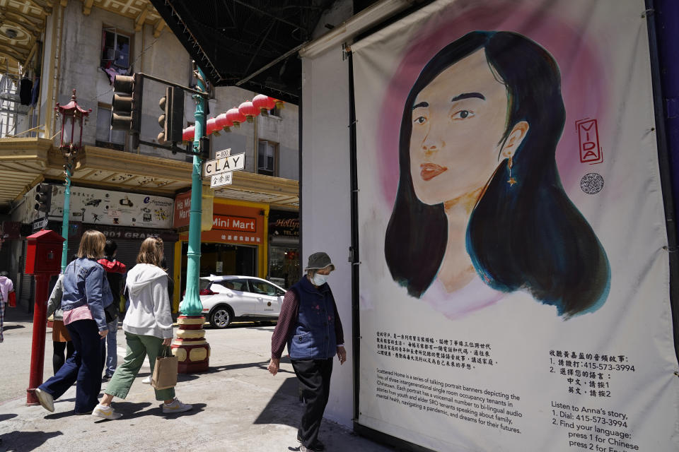 People make their way past a talking portrait banner depicting the lives of three intergenerational single room occupancy Chinatown tenants in San Francisco, Monday, May 23, 2022. Chinatowns and other Asian American enclaves across the U.S. are using art and culture to show they are safe and vibrant hubs nearly three years after the start of the pandemic. From an inaugural arts festival in San Francisco to night markets in New York City, the rise in anti-Asian hate crimes has re-energized these communities and drawn allies and younger generations of Asian and Pacific Islander Americans. (AP Photo/Eric Risberg)