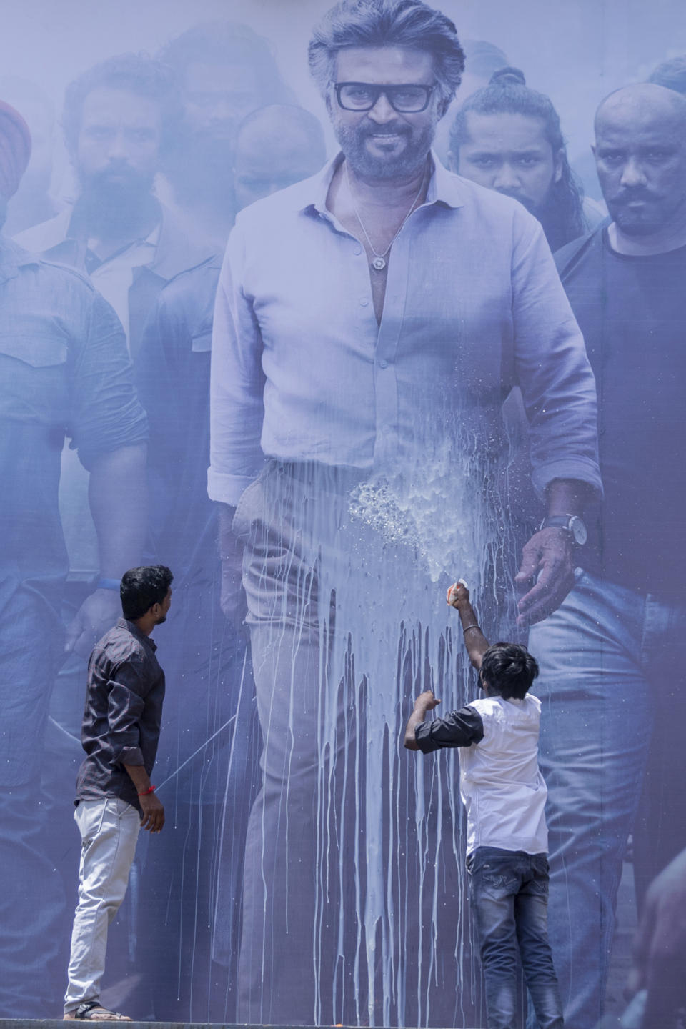 Indian fans pour milk on a huge poster of their superstar Rajinikanth, outside a cinema hall as they celebrate the screening of his latest film "Jailer" in Chennai, India, Thursday, Aug. 10, 2023. (AP Photo/ R. Parthibhan)