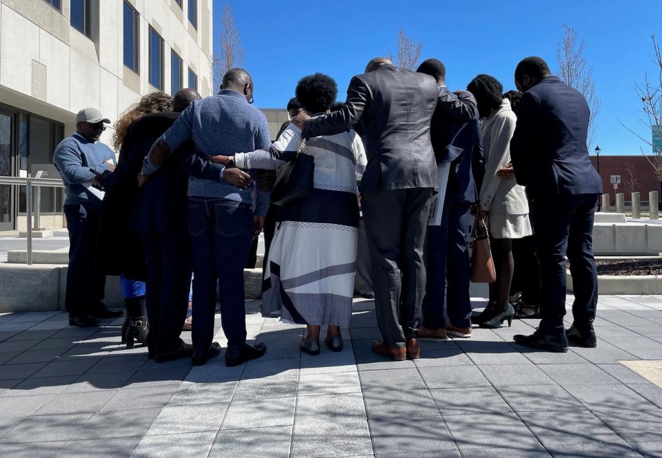 Eric Nshimiye's family and friends pray prior to his detention hearing Friday afternoon at the U.S. District courthouse in Youngstown. Nishimiye, accused of taking part in the Rwandan genocide in the 1990s, will remain behind bars awaiting further court hearings in Boston.