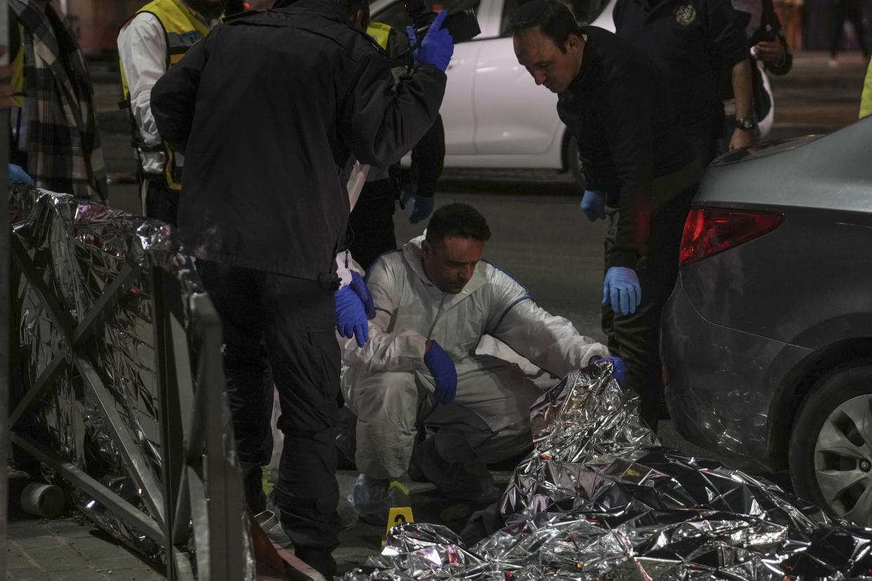 Forensic experts check a body after a shooting attack near a synagogue in Jerusalem , Friday, Jan. 27, 2023. Israel's national rescue service Mada says a gunman killed five people and wounded three others in a shooting near a synagogue Friday night in east Jerusalem in one of the deadliest attacks on Israelis in years. The gunman was shot and reportedly killed. (AP Photo/Mahmoud Illean)