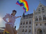 FILE - In this June 14, 2021 file photo a drag queen waves a rainbow flag during an LGBT rights demonstration in front of the Hungarian Parliament building in Budapest, Hungary. Populist Prime Minister Viktor Orban has long used soccer to advance his right-wing politics, and now widespread international criticism of a new Hungarian law that is seen as targeting the LGBT community has turned this month's Euro 2020 tournament into a major stage for his challenge to Europe's liberal values. (AP Photo/Bela Szandelszky, File)