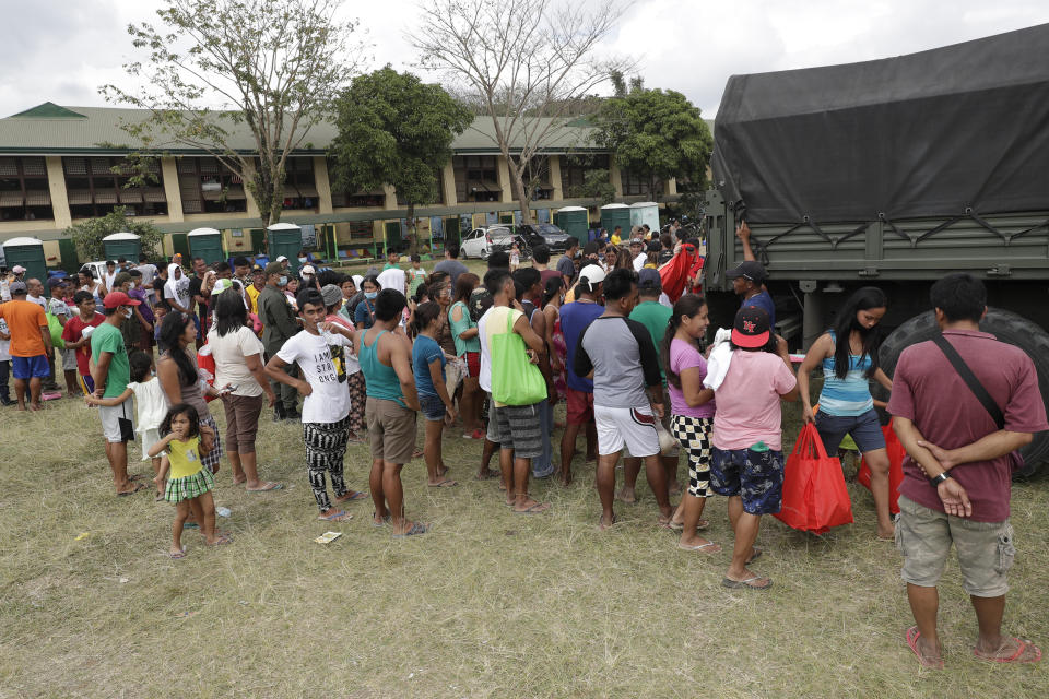 Evacuees gather to receive relief goods at an evacuation center in Alfonso, Cavite province, southern Philippines on Saturday Jan. 18, 2020. The Taal volcano near the Philippine capital emitted more ash clouds Saturday, posing the threat of another eruption. (AP Photo/Aaron Favila)