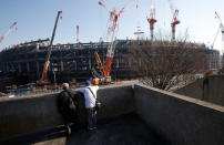 Men looks at the construction site of the New National Stadium, main stadium of Tokyo 2020 Olympics and Paralympics, in Tokyo, Japan December 22, 2017. REUTERS/Issei Kato