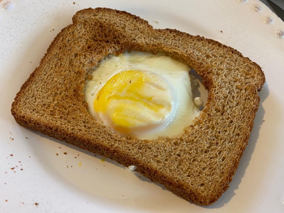 cooked air-fryer egg in a hole on white plate