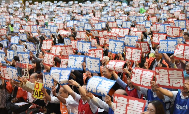 People shout slogans and hold up placards reading "violation of the constitution" (red ones) and "scrap security bills" (blue ones), during a rally in Tokyo on August 26, 2015