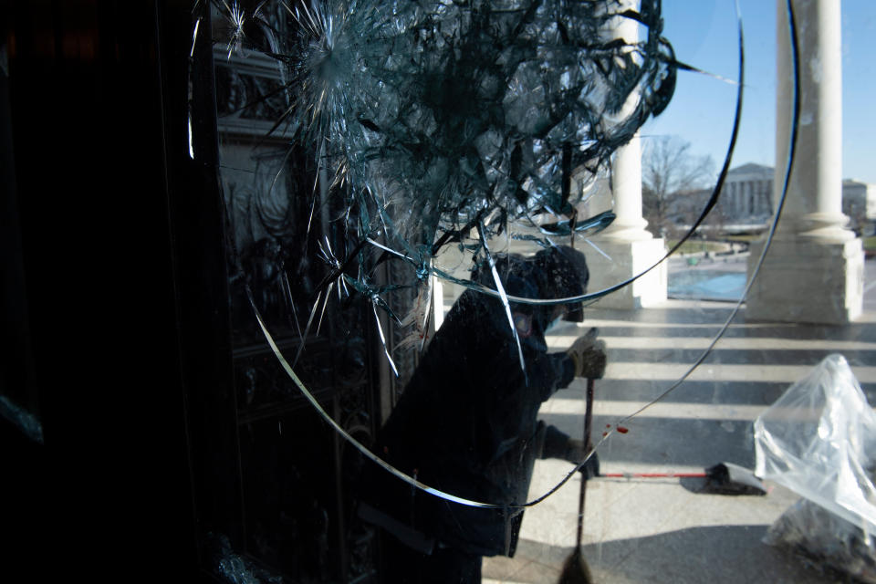 A worker cleans broken glass from one of the entrances to the US Capitol after a pro-Trump mob broke into the building during protests the previous day January 7, 2021, in Washington, DC. (Photo by Brendan Smialowski / AFP) (Photo by BRENDAN SMIALOWSKI/AFP via Getty Images)