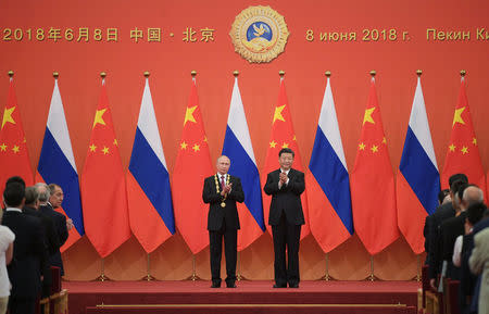 Chinese President Xi Jinping (R) stands next to Russian President Vladimir Putin after presenting him with the Friendship Medal during a ceremony in the Great Hall of the People in Beijing, China June 8, 2018. Sputnik/Alexei Druzhinin/Kremlin via REUTERS